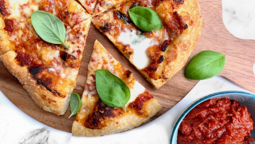 Home baker stretching pizza dough by hand in a kitchen, aiming for restaurant-quality crust.
