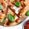 Home baker stretching pizza dough by hand in a kitchen, aiming for restaurant-quality crust.