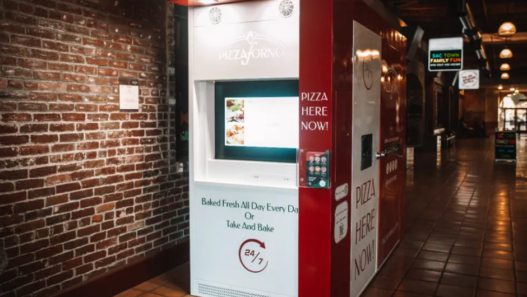 Red-and-white PizzaForno vending machine dispensing a freshly baked 12-inch pizza in California.
