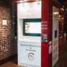 Red-and-white PizzaForno vending machine dispensing a freshly baked 12-inch pizza in California.