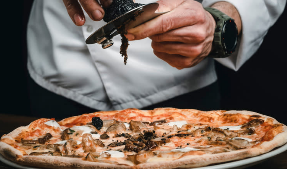 Chef slicing the world’s most expensive pizza topped with wild luxury ingredients, showcased in an upscale setting.