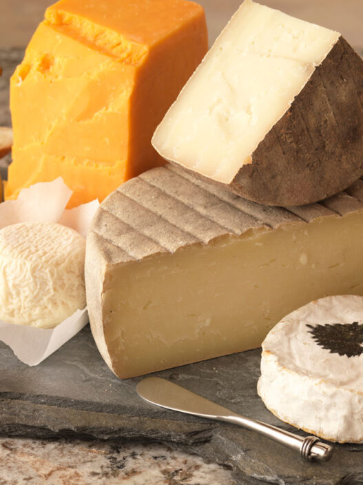 Wedge of soft-ripened cheese like Brie being cut, showing creamy interior under bloom rind.