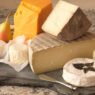 Wedge of soft-ripened cheese like Brie being cut, showing creamy interior under bloom rind.