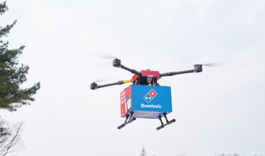 Domino’s drone in mid-air delivering pizza to a New Zealand couple, marking the world’s first commercial drone pizza delivery.