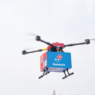 Domino’s drone in mid-air delivering pizza to a New Zealand couple, marking the world’s first commercial drone pizza delivery.