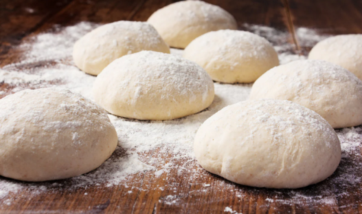 Eight individually frozen 240 g pizza dough balls arranged neatly in clear packaging.