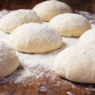 Eight individually frozen 240 g pizza dough balls arranged neatly in clear packaging.