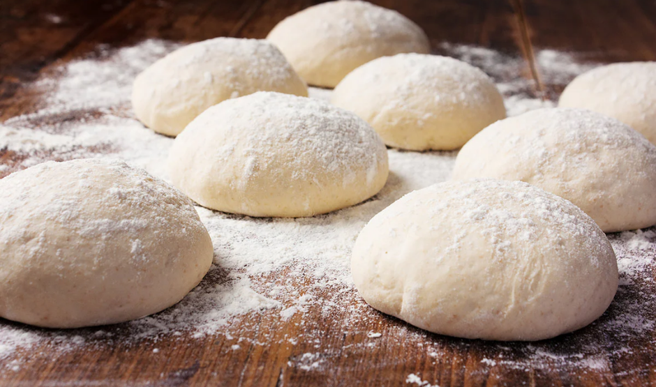 Eight individually frozen 240 g pizza dough balls arranged neatly in clear packaging.