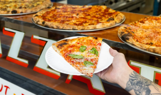 Thin-crust New York–style pizza slice from Outta Sight Pizza in San Francisco’s Chinatown, featuring melty cheese and charred edges.