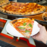 Thin-crust New York–style pizza slice from Outta Sight Pizza in San Francisco’s Chinatown, featuring melty cheese and charred edges.