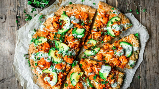 Hot and spicy Buffalo Cauliflower Vegan Pizza topped with vegan cheese, red onion, and ranch drizzle on a crispy crust