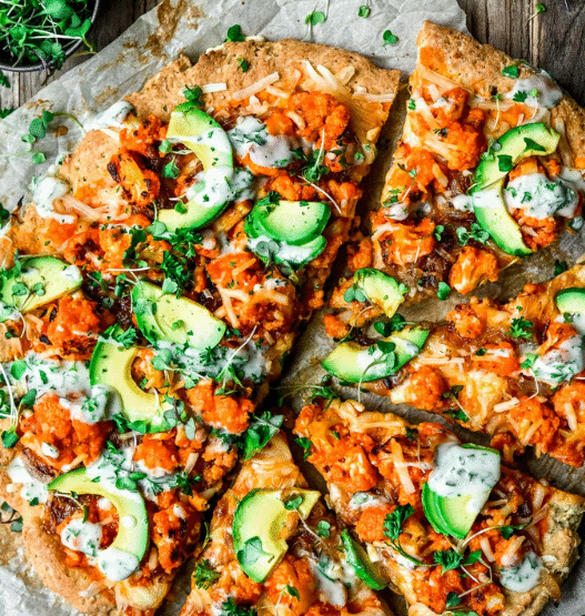 Hot and spicy Buffalo Cauliflower Vegan Pizza topped with vegan cheese, red onion, and ranch drizzle on a crispy crust