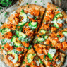 Hot and spicy Buffalo Cauliflower Vegan Pizza topped with vegan cheese, red onion, and ranch drizzle on a crispy crust