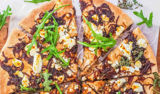 Freshly baked Caramelized Onion & Goat Cheese Pizza topped with thyme on a golden crust
