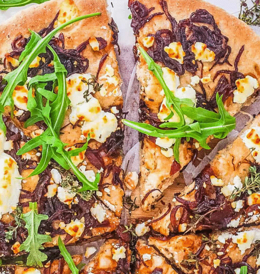 Freshly baked Caramelized Onion & Goat Cheese Pizza topped with thyme on a golden crust