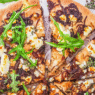 Freshly baked Caramelized Onion & Goat Cheese Pizza topped with thyme on a golden crust
