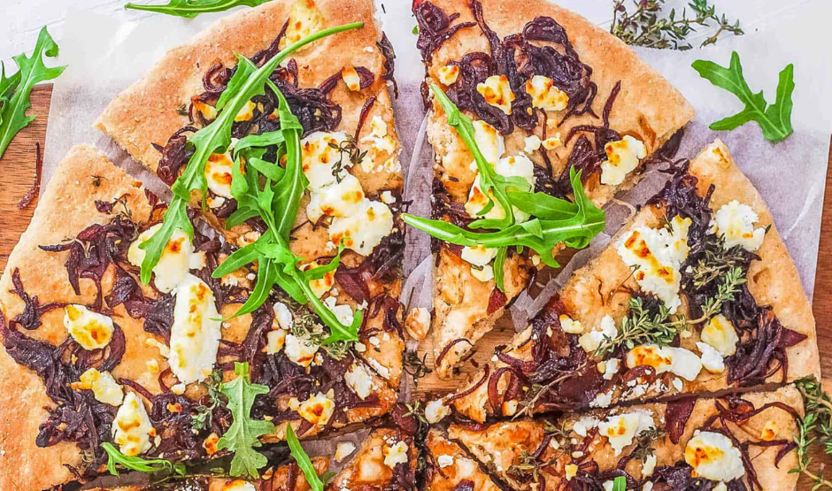Freshly baked Caramelized Onion & Goat Cheese Pizza topped with thyme on a golden crust