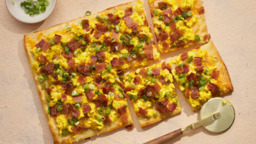 Chorizo breakfast pizza topped with roasted potatoes, sunny-side eggs, and cilantro on a golden crust