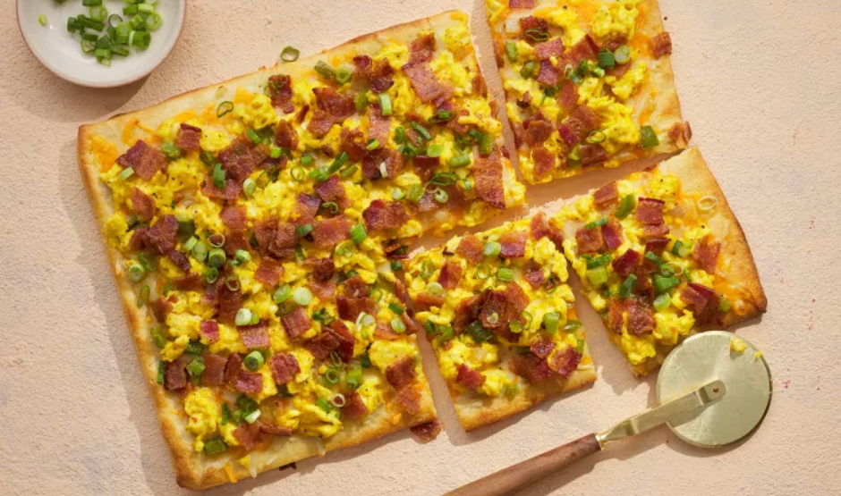 Chorizo breakfast pizza topped with roasted potatoes, sunny-side eggs, and cilantro on a golden crust