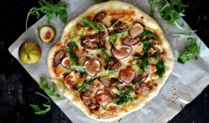 Duck Confit & Fig Pizza topped with goat cheese, arugula, and balsamic glaze on a rustic wooden board – Downtown LA gourmet style.