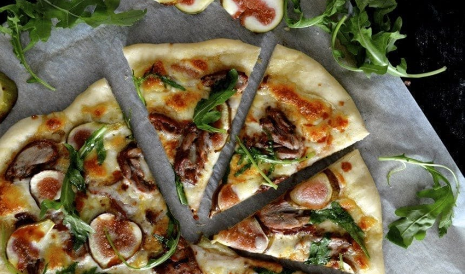 Duck Confit & Fig Pizza topped with goat cheese, arugula, and balsamic glaze on a rustic wooden board – Downtown LA gourmet style.