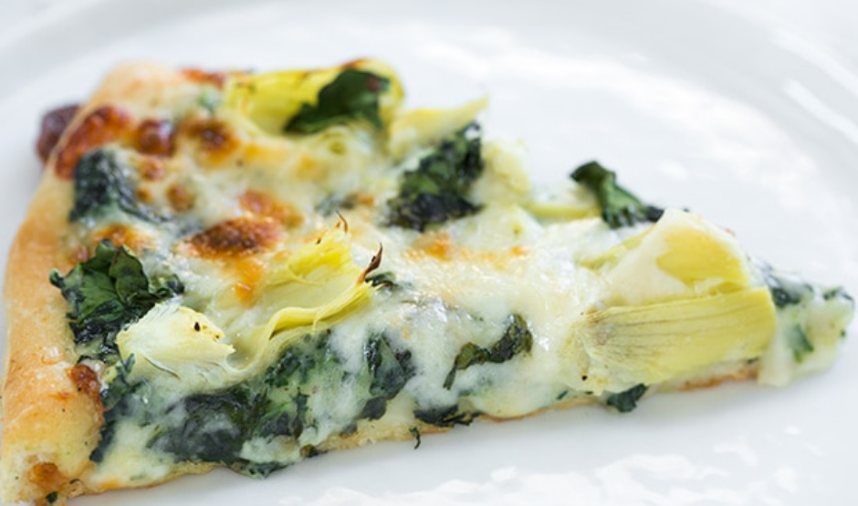Grilled artichoke and spinach pizza with feta and mozzarella on a golden crust, served on a wooden board – inspired by Venice Beach flavors.