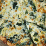 Grilled artichoke and spinach pizza with feta and mozzarella on a golden crust, served on a wooden board – inspired by Venice Beach flavors.