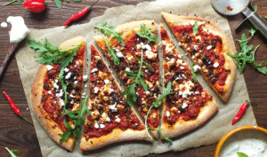 Wood-fired Lamb Merguez Pizza topped with feta, red onion, and fresh parsley on a rustic crust