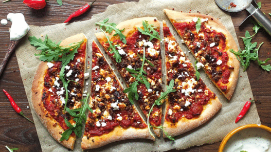 Wood-fired Lamb Merguez Pizza topped with feta, red onion, and fresh parsley on a rustic crust