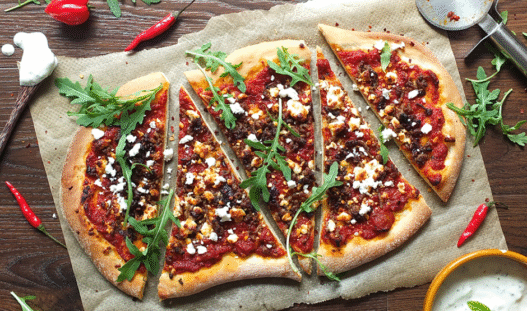 Wood-fired Lamb Merguez Pizza topped with feta, red onion, and fresh parsley on a rustic crust