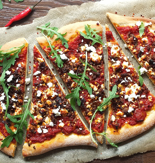 Wood-fired Lamb Merguez Pizza topped with feta, red onion, and fresh parsley on a rustic crust