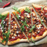 Wood-fired Lamb Merguez Pizza topped with feta, red onion, and fresh parsley on a rustic crust