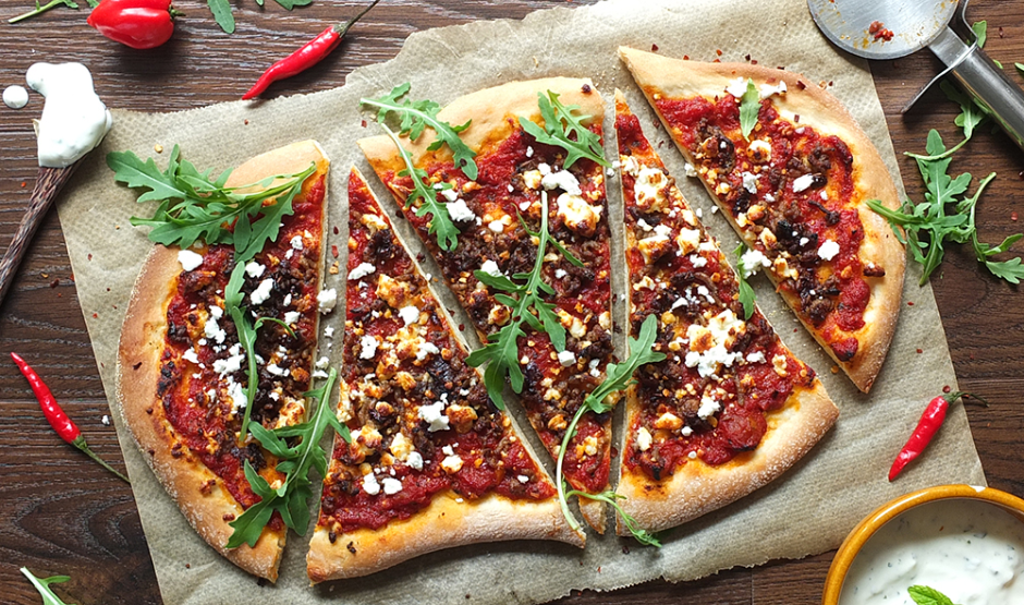 Wood-fired Lamb Merguez Pizza topped with feta, red onion, and fresh parsley on a rustic crust