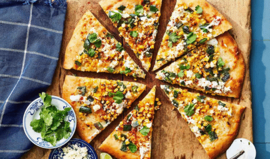 Mexican Street Corn Pizza topped with roasted corn, cotija cheese, red onion, cilantro, and chili lime crema on a golden crispy crust.