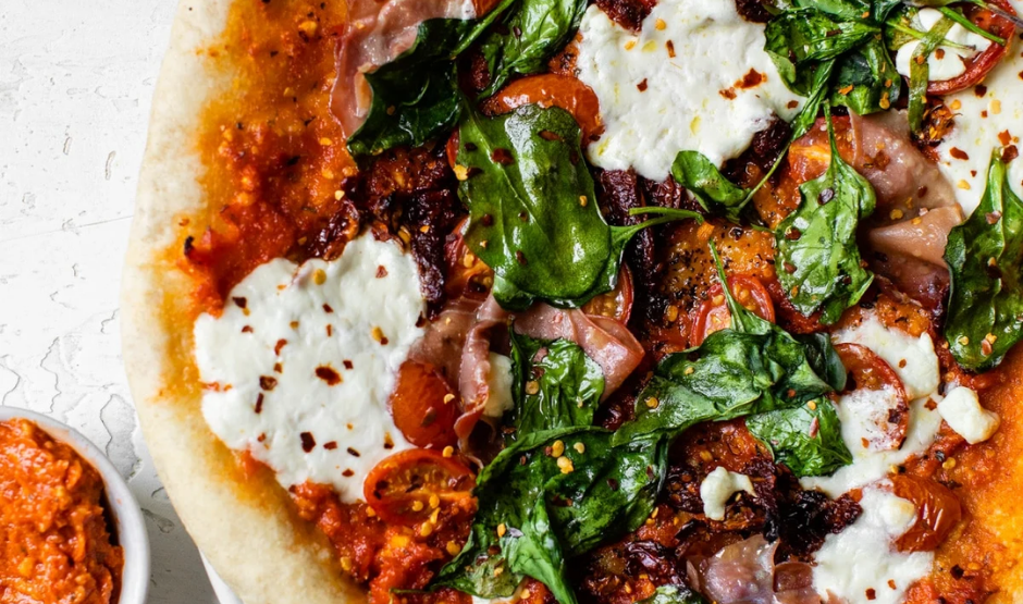 Sun-dried tomato pesto pizza topped with whipped ricotta and fresh basil