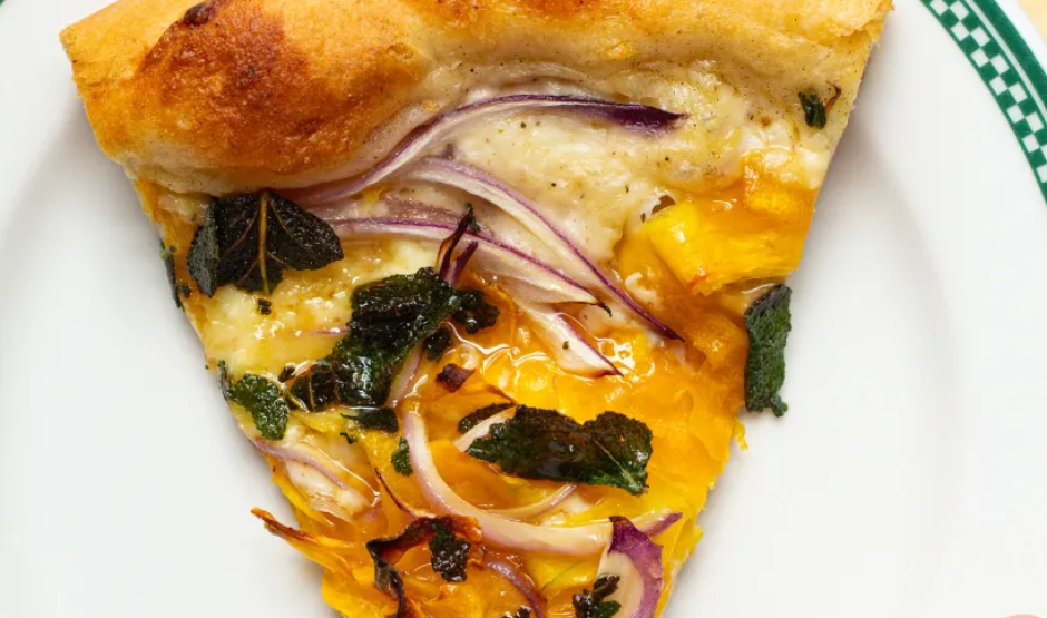 Close-up of Autumn Glow Pizza with roasted spaghetti squash strands, melted mozzarella, and crispy sage leaves on a golden-brown crust