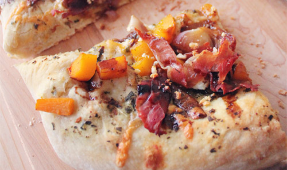 Pumpkin & Prosciutto Pizza topped with arugula, balsamic glaze, and shaved Parmesan on a golden crust