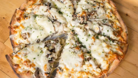 Overhead shot of golden-baked Truffle Mac and Cheese Pizza with bubbling cheese and truffle oil drizzle on a wooden board.
