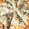 Overhead shot of golden-baked Truffle Mac and Cheese Pizza with bubbling cheese and truffle oil drizzle on a wooden board.