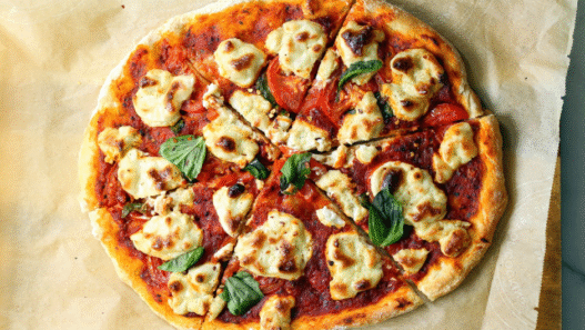 Vegan cashew cheese pizza with roasted vegetables, fresh arugula, and balsamic glaze on a golden crust