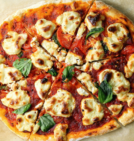 Vegan cashew cheese pizza with roasted vegetables, fresh arugula, and balsamic glaze on a golden crust