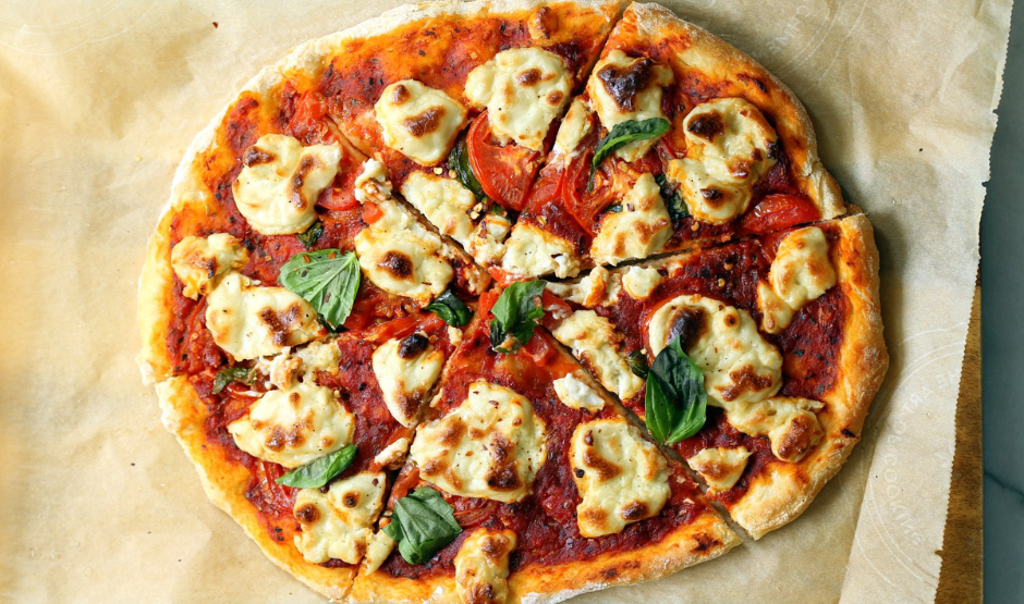 Vegan cashew cheese pizza with roasted vegetables, fresh arugula, and balsamic glaze on a golden crust