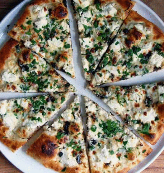 Ricotta garlic white pizza topped with mozzarella, roasted garlic, and parsley on a rustic wooden board