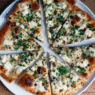 Ricotta garlic white pizza topped with mozzarella, roasted garlic, and parsley on a rustic wooden board