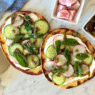 Zaatar & Labneh Flatbread Pizza topped with cherry tomatoes, herbs, and red onion on a white plate