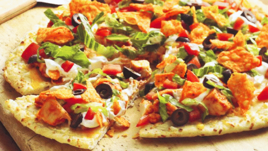 A freshly baked Chicken & Purple Potato Street Taco Pizza with melted cheese, purple potato slices, red onion, and cilantro on a wooden board