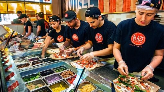 Freshly baked Blaze Pizza being pulled from a fast-fire’d oven with custom toppings