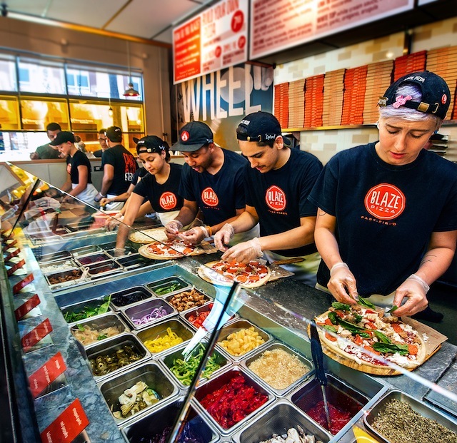 Freshly baked Blaze Pizza being pulled from a fast-fire’d oven with custom toppings