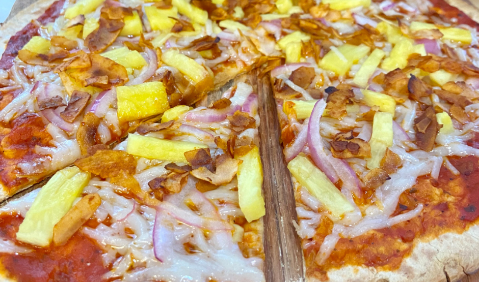 Coconut Bacon Vegan Hawaiian Pizza topped with pineapple, vegan cheese, red onions, and coconut bacon on a golden crust