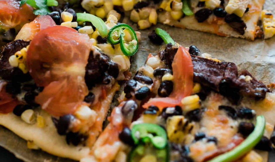 Carne Asada Street Taco Pizza topped with grilled steak, avocado, salsa, and cilantro on a crispy artisan crust